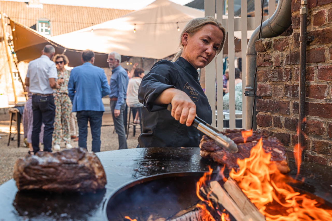 Kok grilt rib-eye boven open vuur bij een winterbarbecue